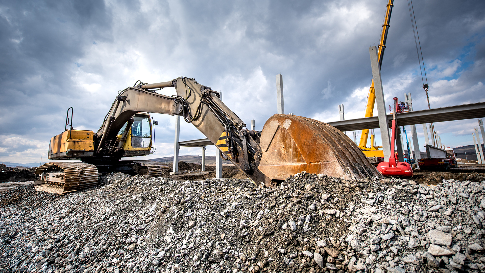 Heavy duty industrial excavator loading gravel on construction site. Details of building site